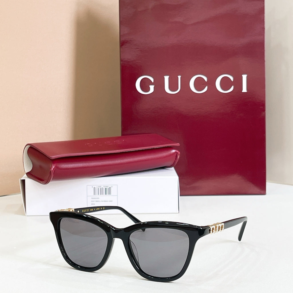 Gucci sunglasses, black frame with gray tinted lenses and gold-tone logo accents