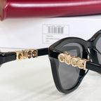 Gucci sunglasses, close-up black frame with gold-tone GG bar detail and gray lenses