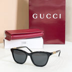 Gucci sunglasses, black frame with black tinted lenses and gold-tone logo accents