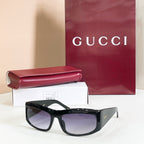 Gucci sunglasses with black oversized frames and purple-tinted lenses.