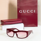 Gucci sunglasses with burgundy oversized frames and pink lenses.
