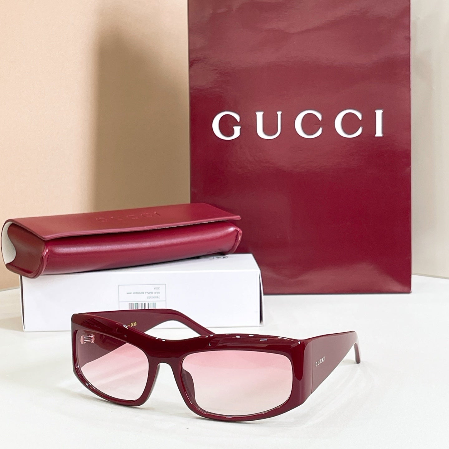 Gucci sunglasses with burgundy oversized frames and pink lenses.