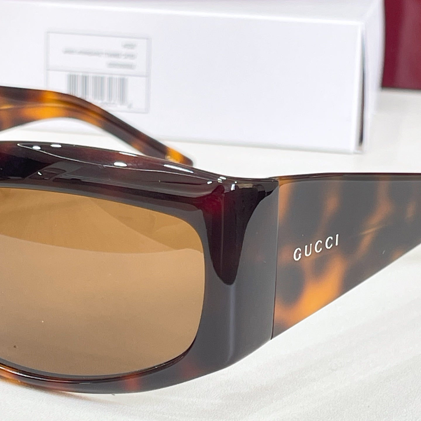 Gucci sunglasses close-up with dark tortoiseshell frame and brown lenses.