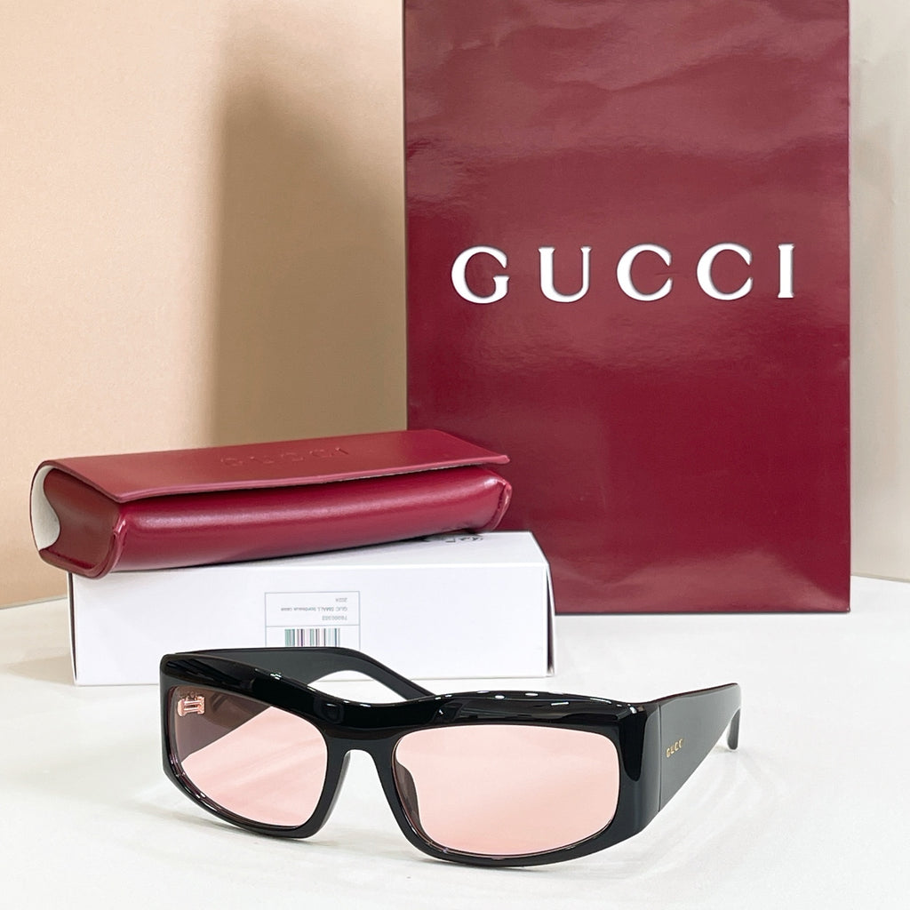 Gucci sunglasses with black oversized frames and pink-tinted lenses.