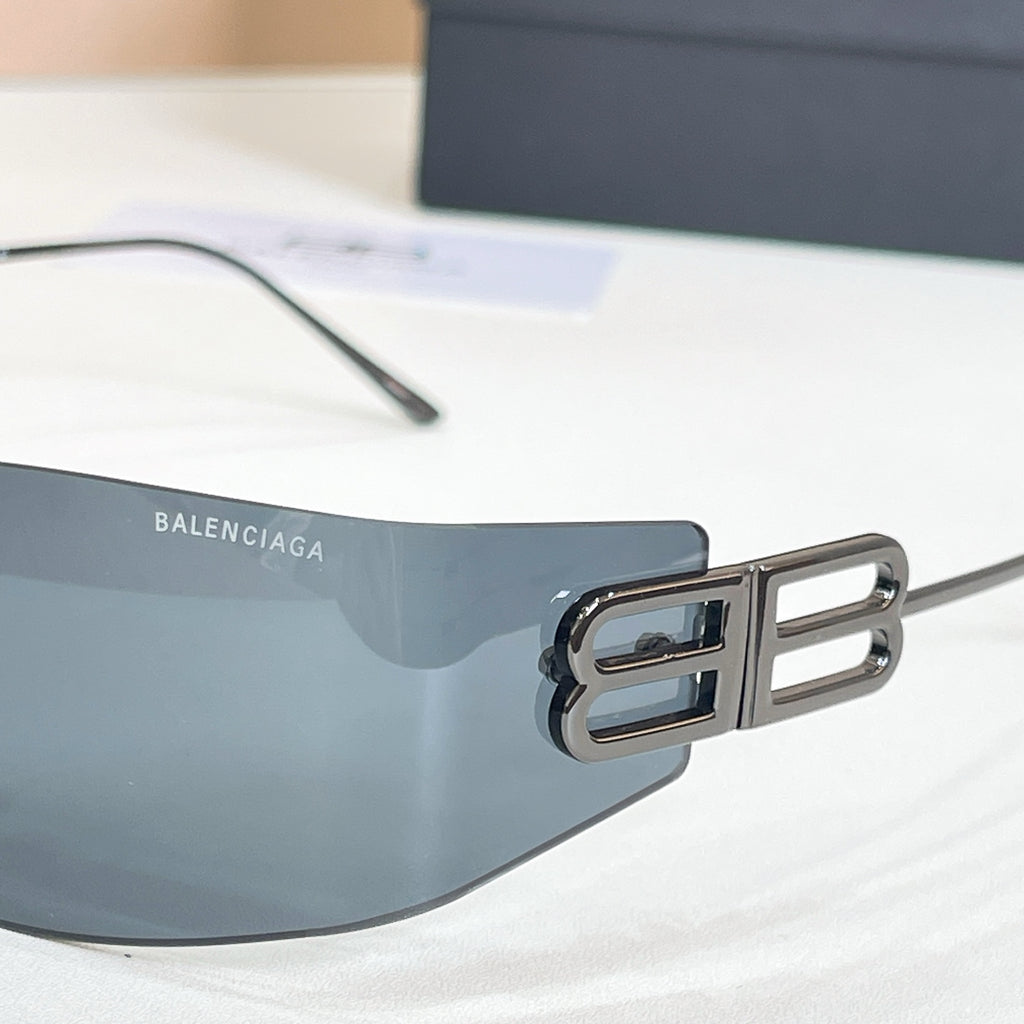 Sunglasses temple close-up with gold B logo and dark tinted lens, metal frame