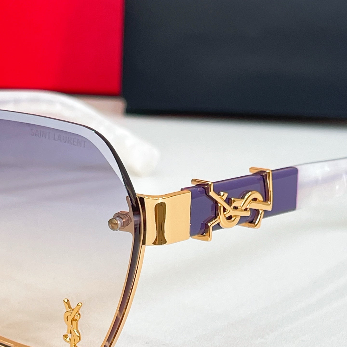 Gold-tone temple ornament with purple inlay on oversized sunglasses
