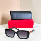 Black oversized sunglasses with dark lenses and gold logo detail on temples