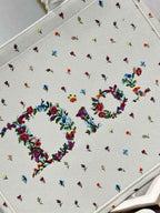 Close-up of white Dior tote bag fabric with multicolor bow and floral embroidery