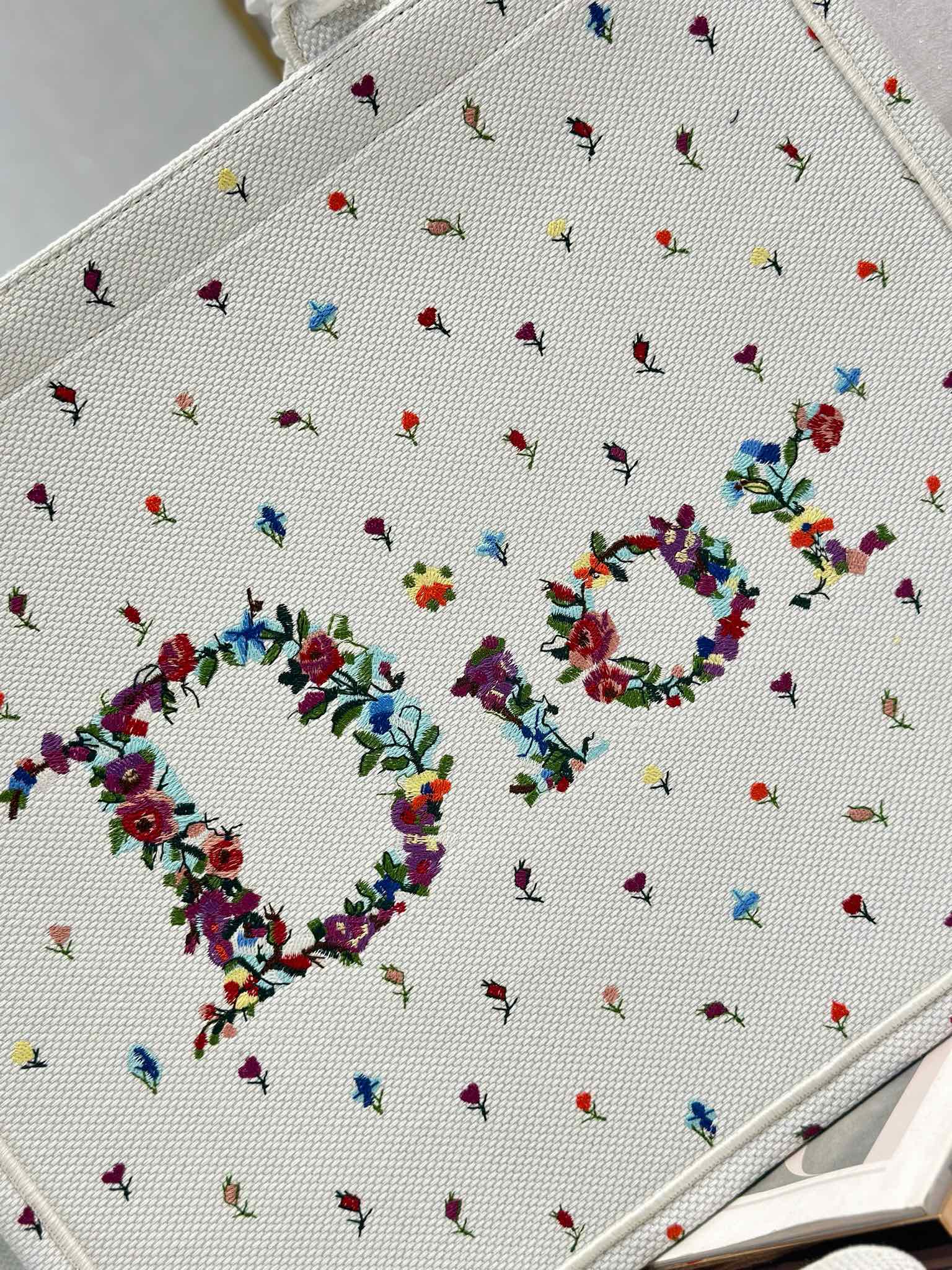 Close-up of white Dior tote bag fabric with multicolor bow and floral embroidery