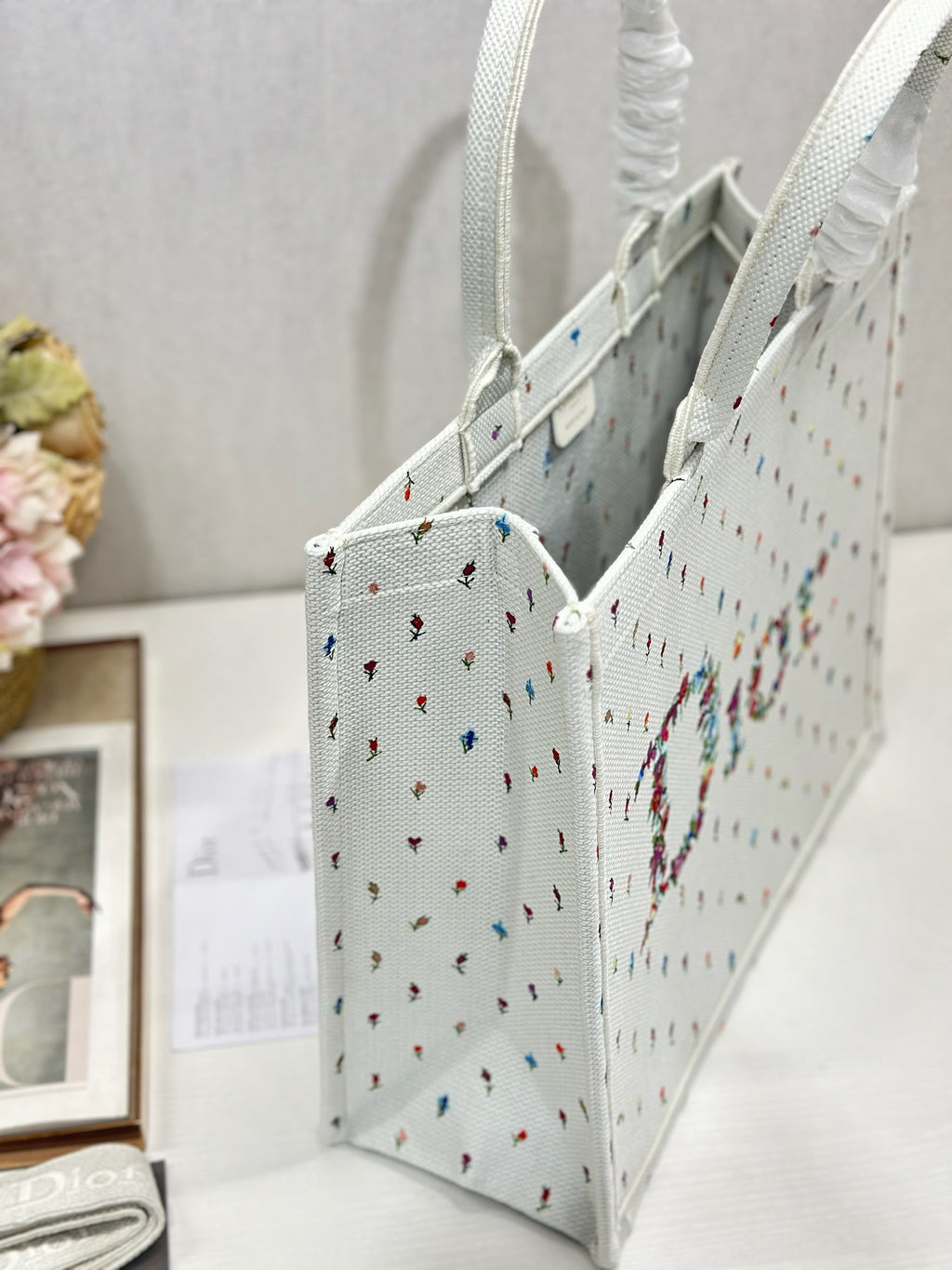 Side view of white Dior tote bag with ruched handle and multicolor embroidery