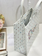 Side view of white Dior tote bag with ruched handle and multicolor embroidery