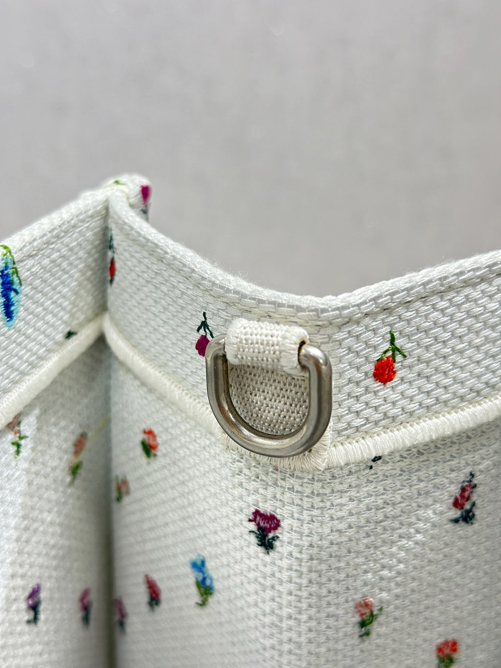 White Dior tote bag side with metal D-ring detail and small multicolor motifs