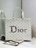 White Dior tote bag with ruched top handles and multicolor embroidered pattern