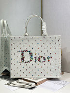 White Dior tote bag with ruched top handles and multicolor embroidered pattern