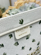Dior label on the inner strap of a white tote bag with yellow floral and cactus print.