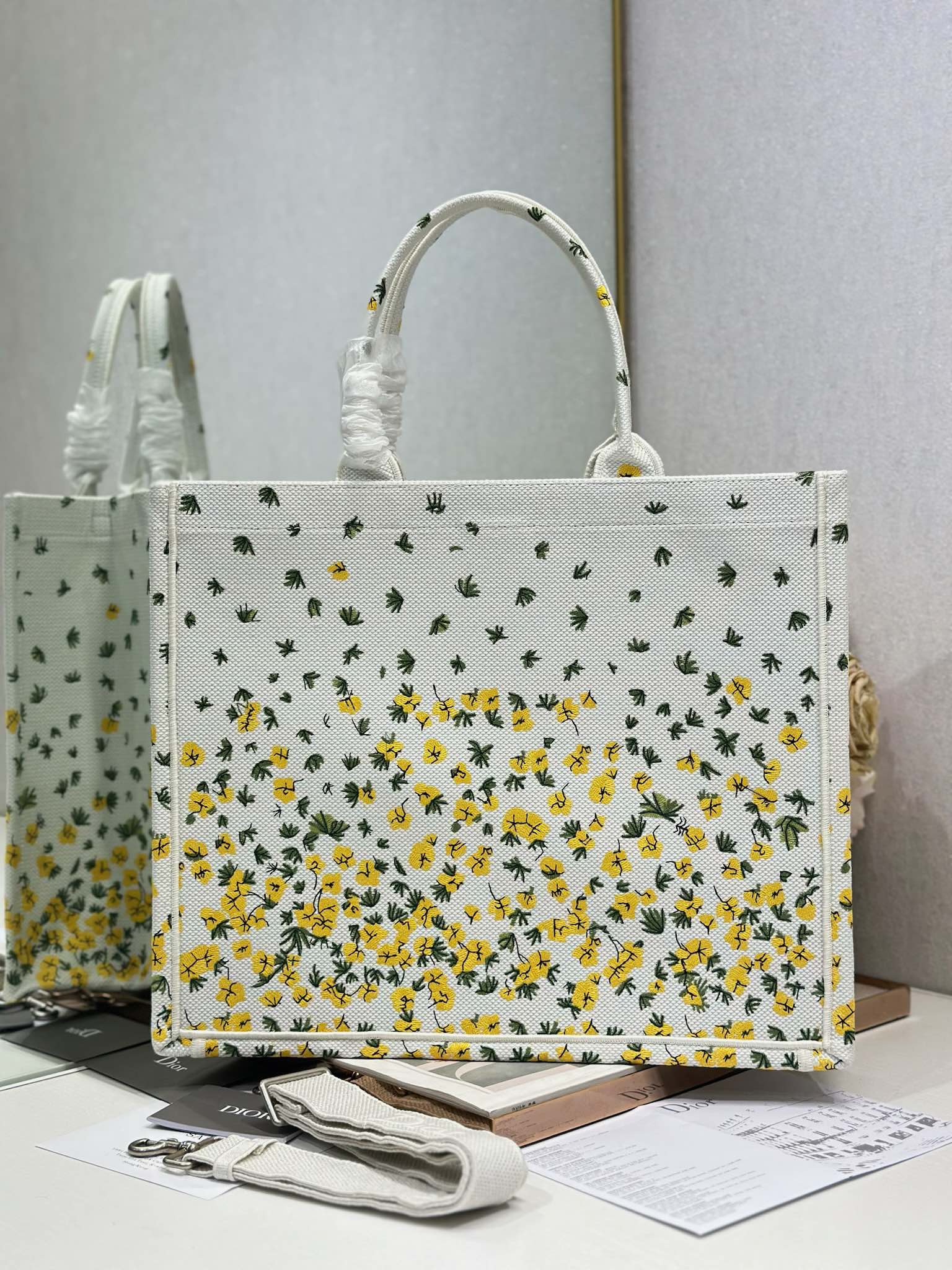 Dior tote bag with white background and yellow floral cactus print, top handles and open top.