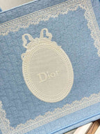Light blue Dior tote bag front close-up with oval Dior logo patch and trim