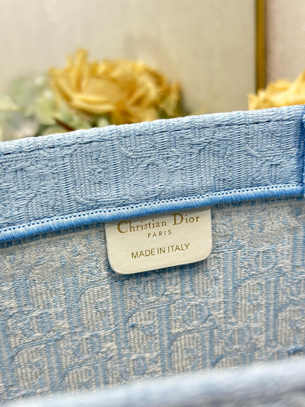 Light blue Dior tote bag fabric tag reading “Christian Dior Paris, Made in Italy”