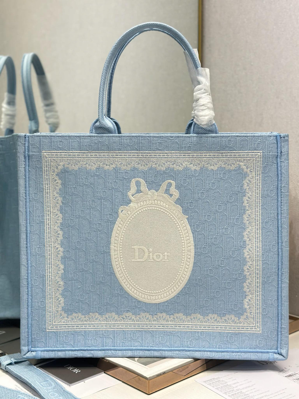 Light blue Dior tote bag with oval Dior logo emblem and rope-like top handles
