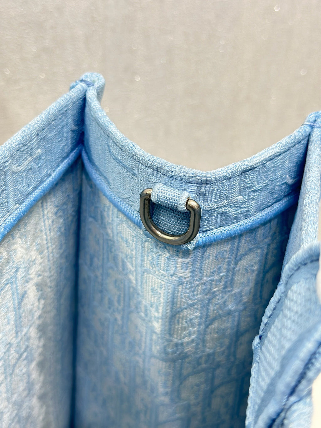 Light blue Dior tote bag corner with metal D-ring strap loop