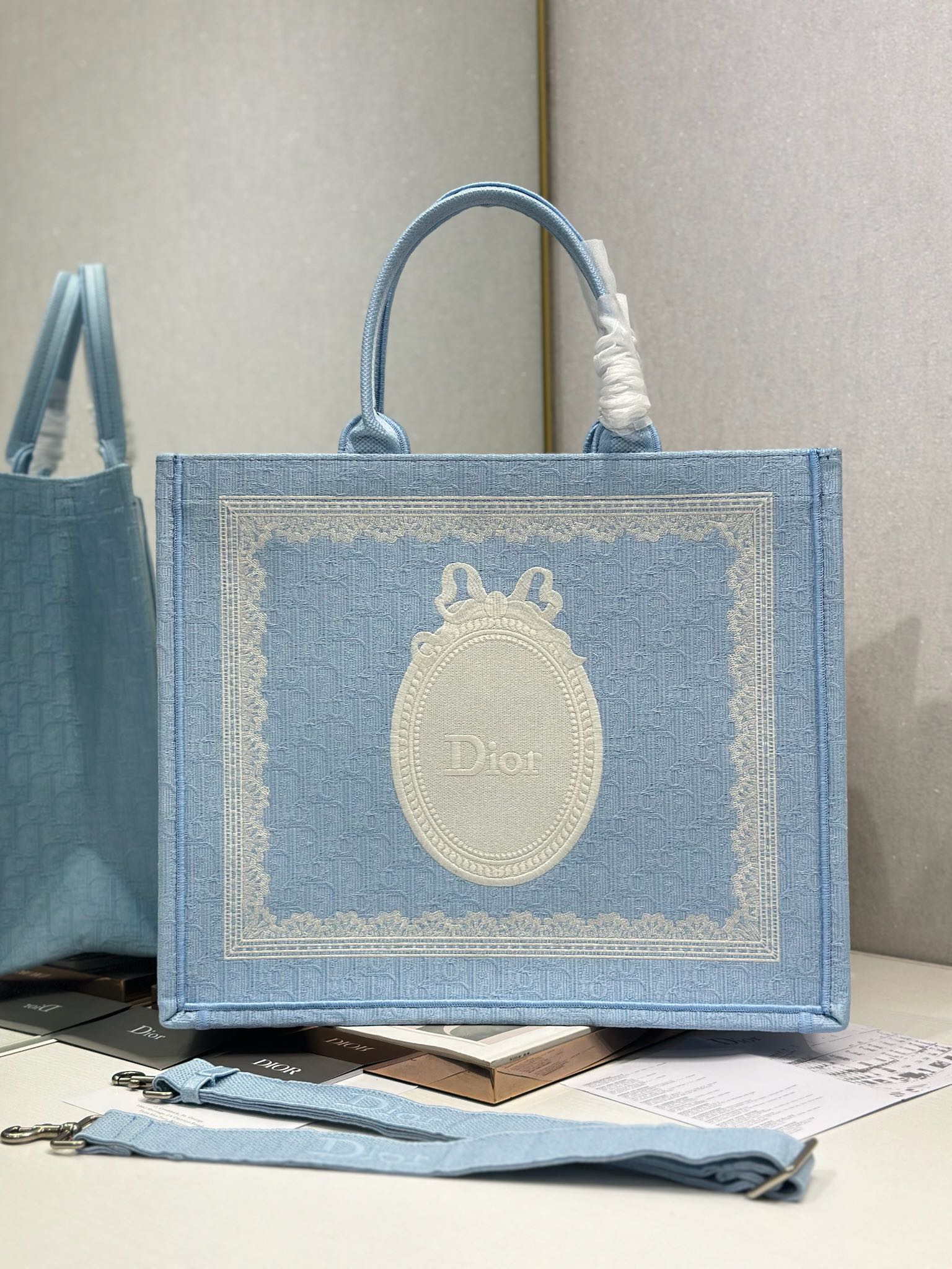 Light blue Dior tote bag with embroidered oval Dior logo patch and top handles