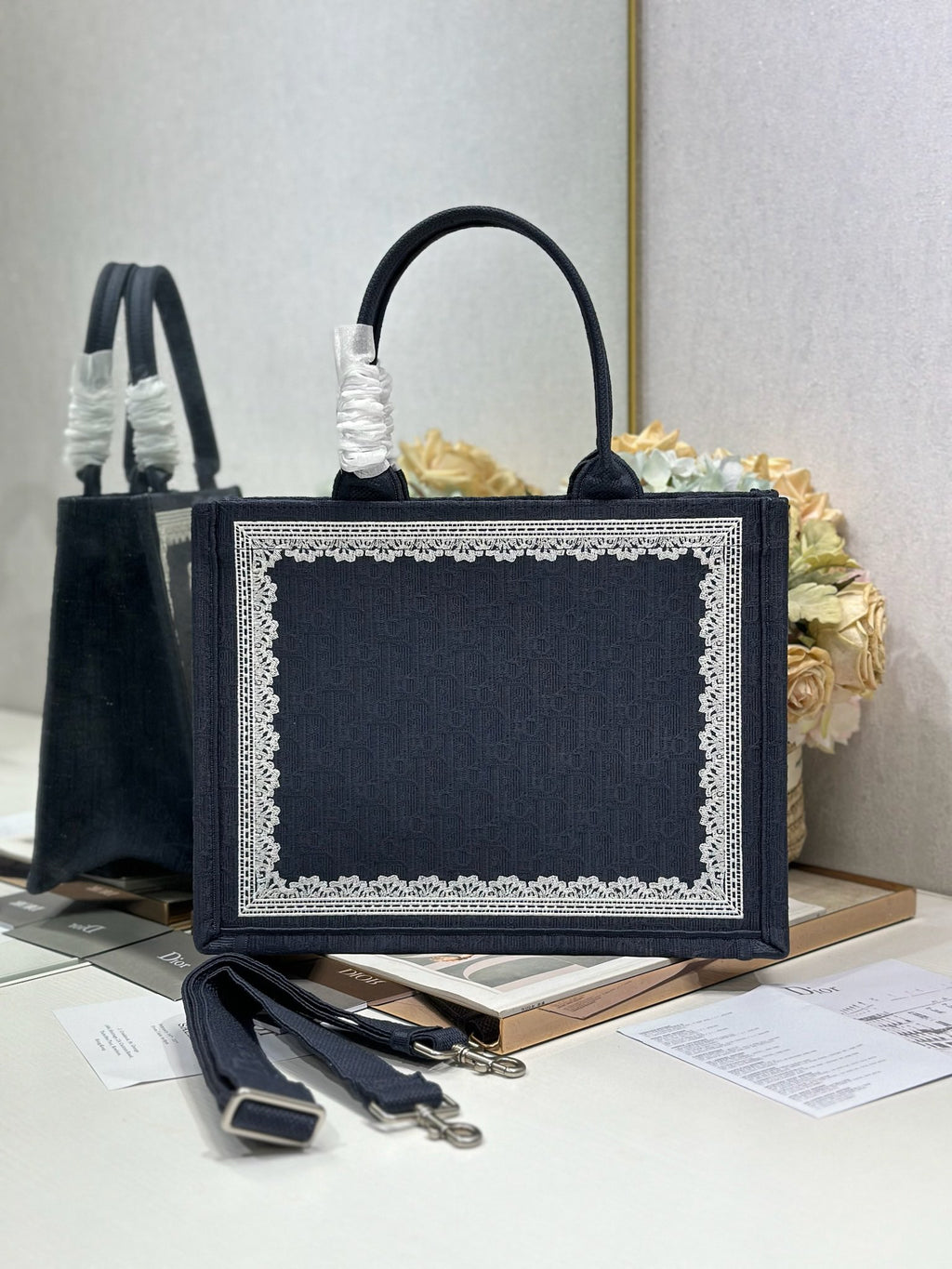 Navy Dior tote bag with front logo plaque, top handles, and decorative lace trim