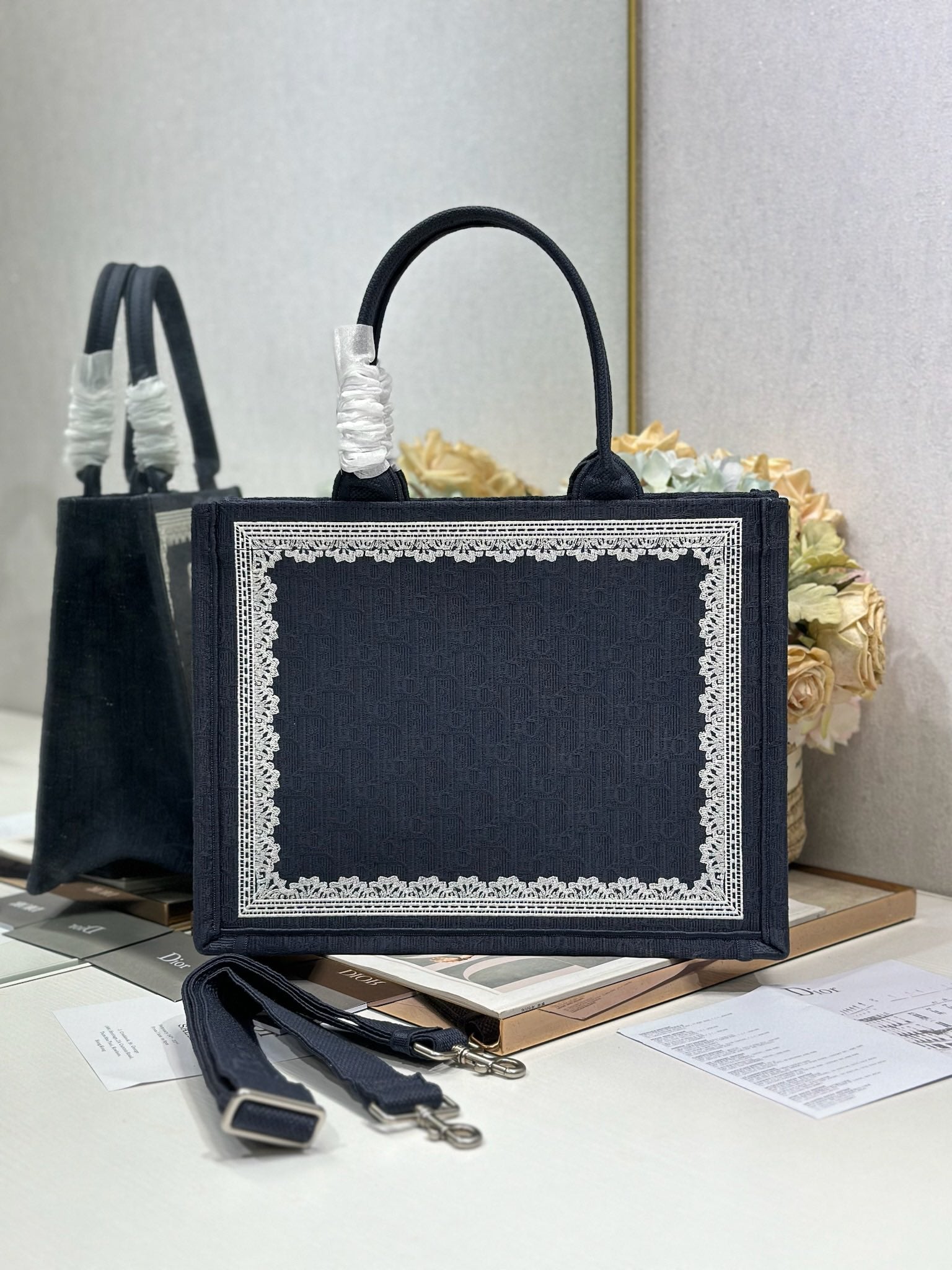 Navy Dior tote bag with front logo plaque, top handles, and decorative lace trim