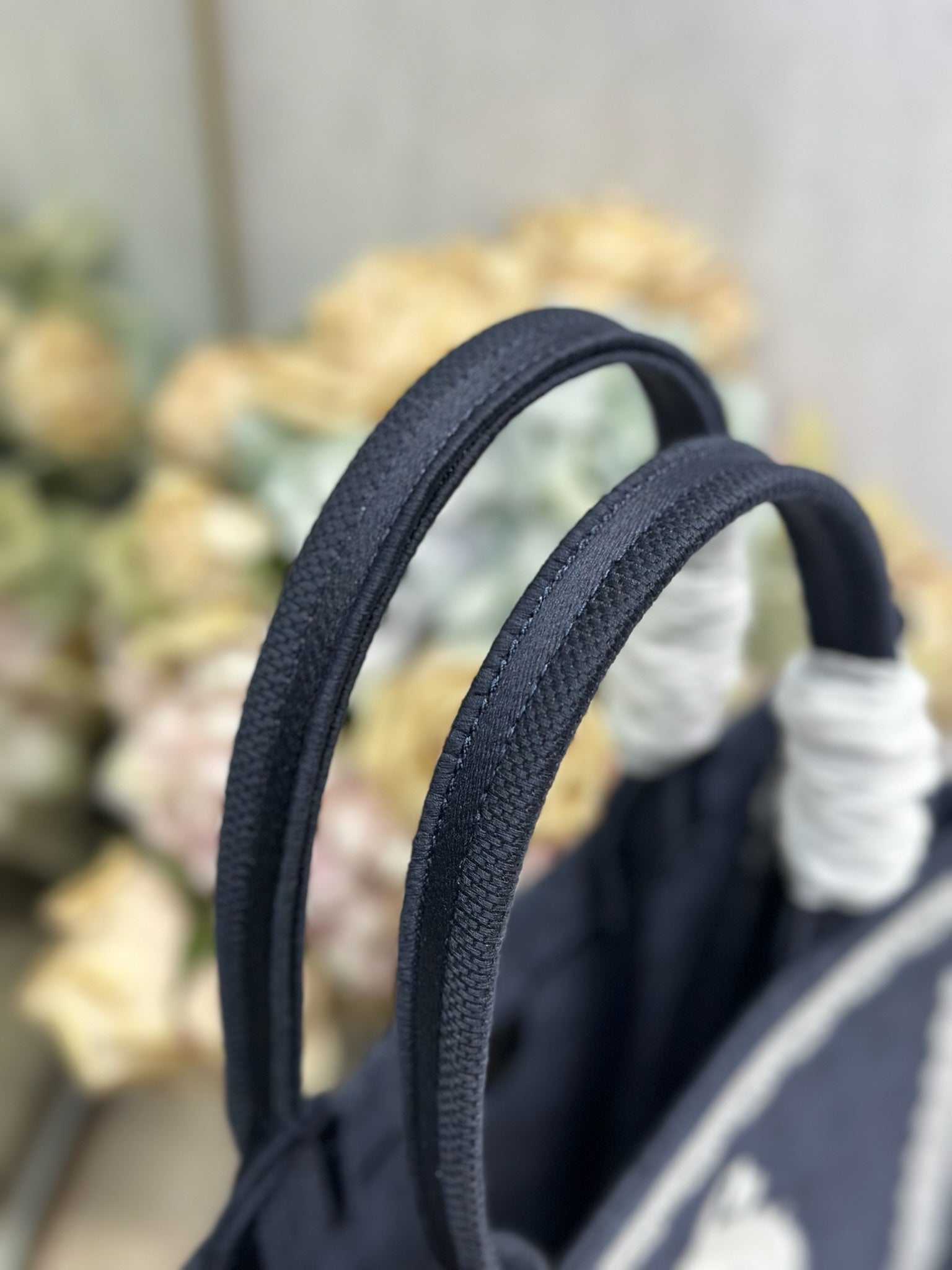 Navy Dior tote bag top handles with gathered white fabric details on the handle grips