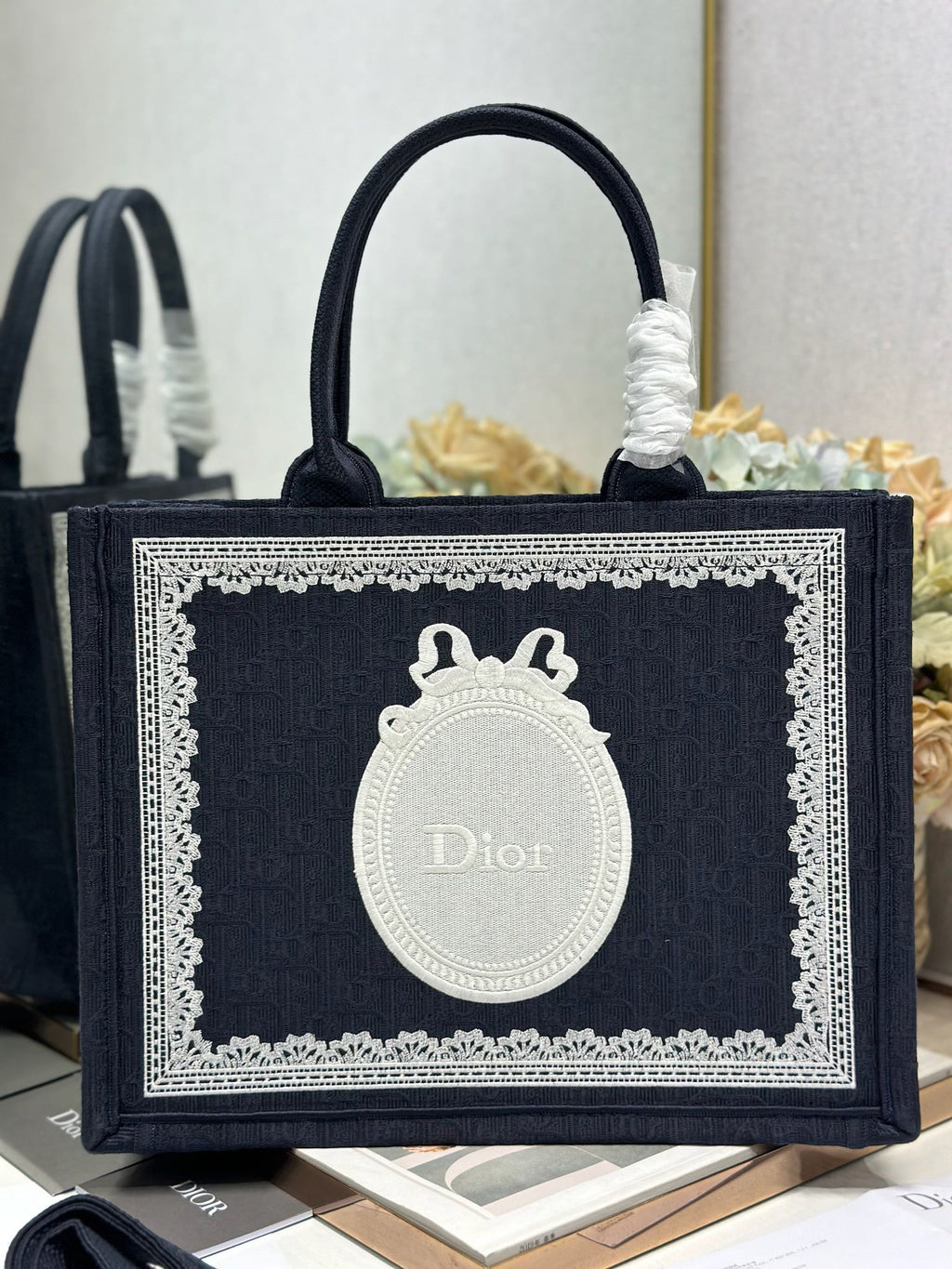Navy Dior tote bag front view with white medallion Dior logo and lace-edged frame