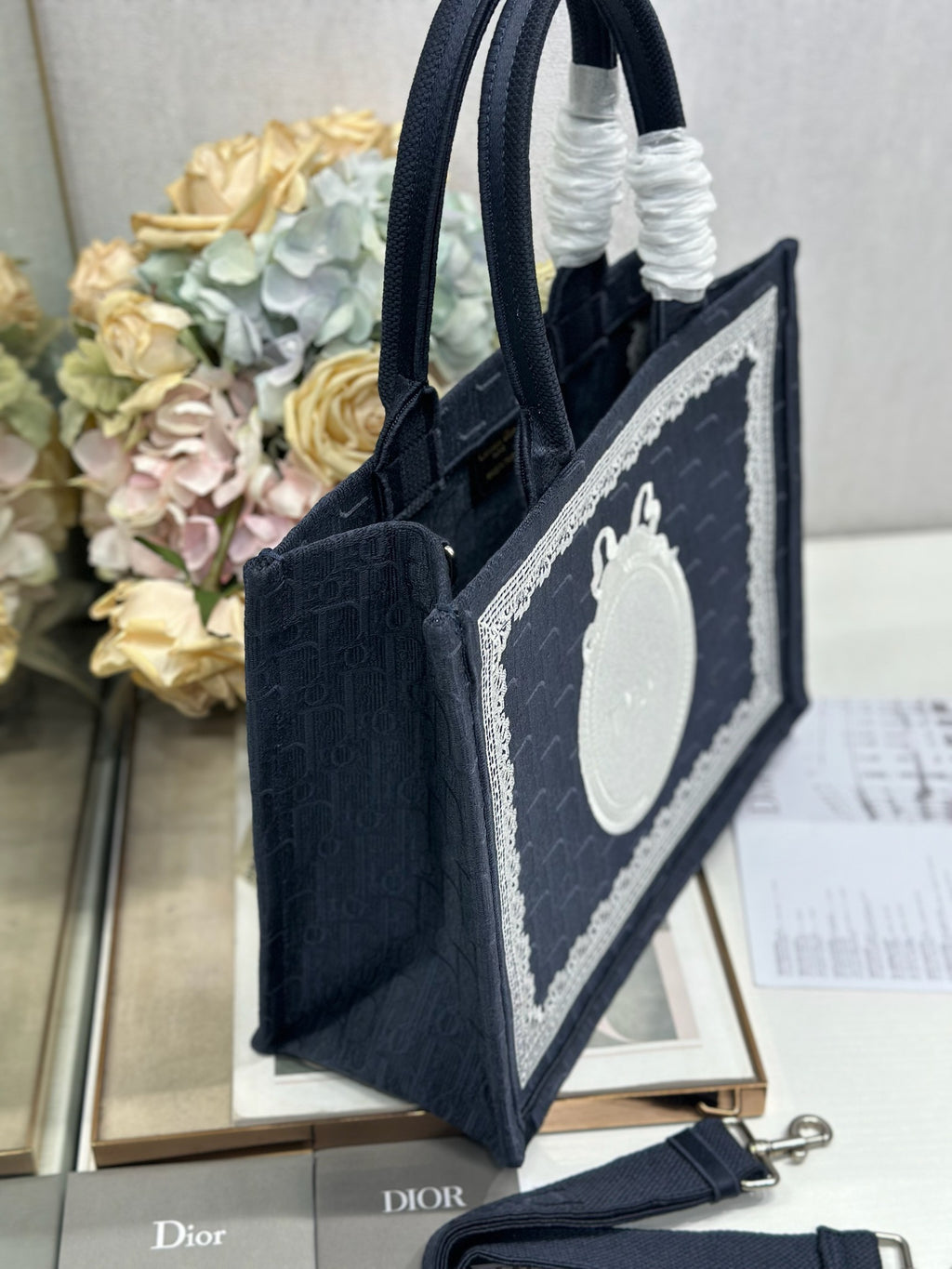 Navy Dior tote bag shown from the side with front logo panel and structured base