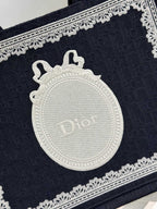 Close-up of navy Dior tote bag front with embossed white medallion logo and trim