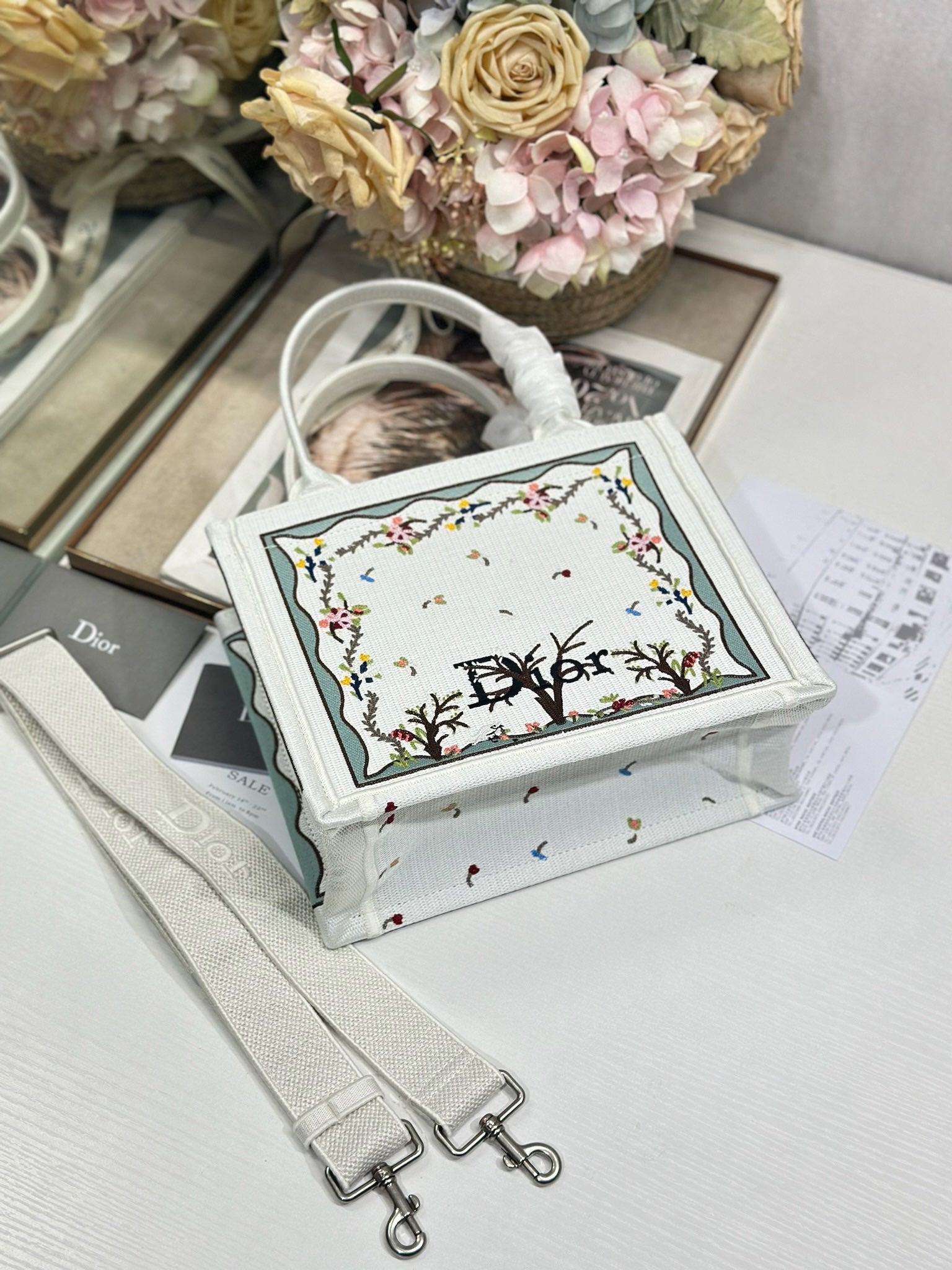 Dior tote bag with embroidered front panel, light gray strap, and visible crossbody hardware
