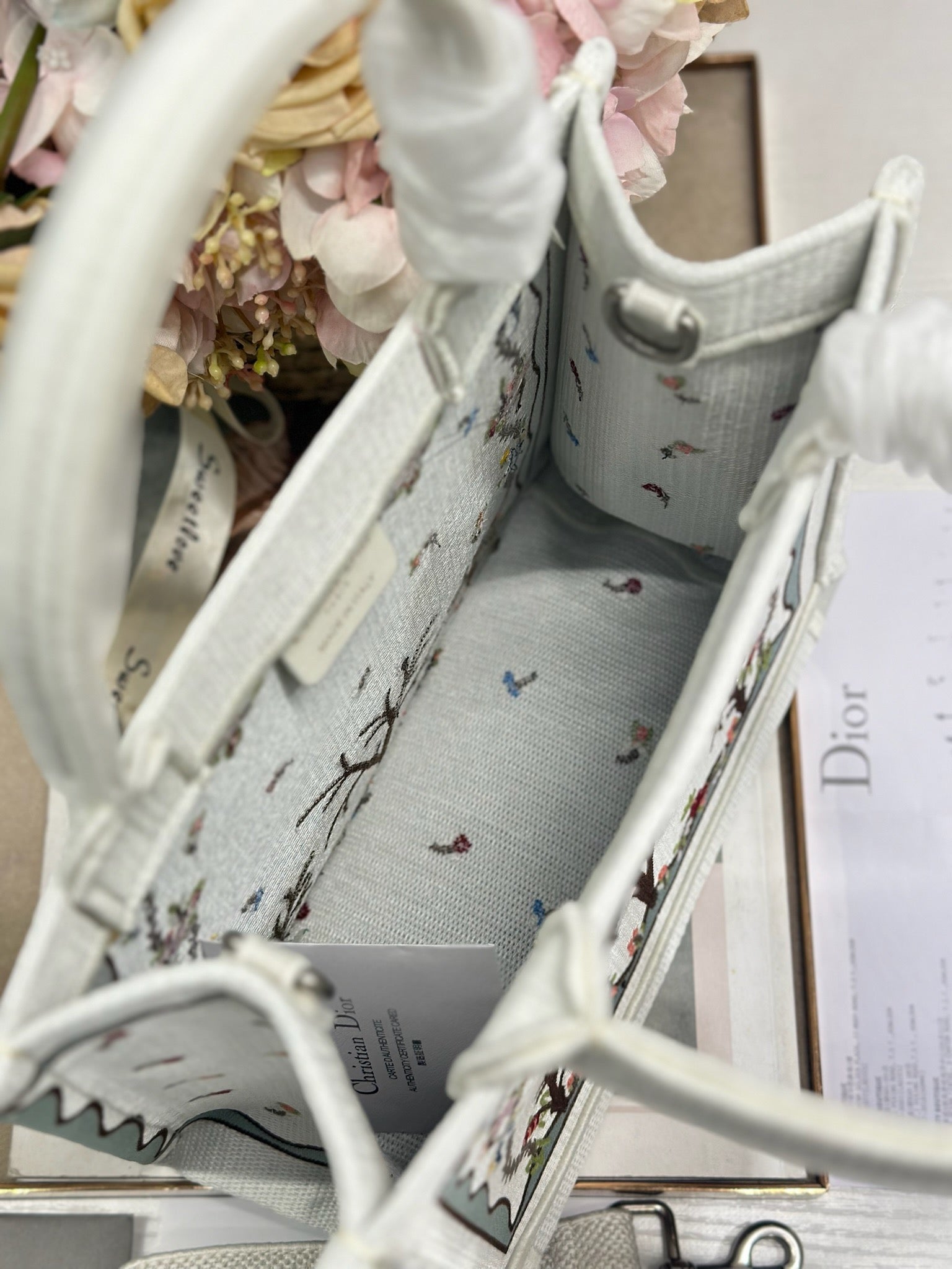 Dior tote bag interior view with light gray lining and small embroidered motifs