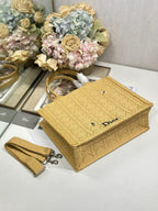 Dior gold handbag with textured pattern and decorative strap, shown folded on display.