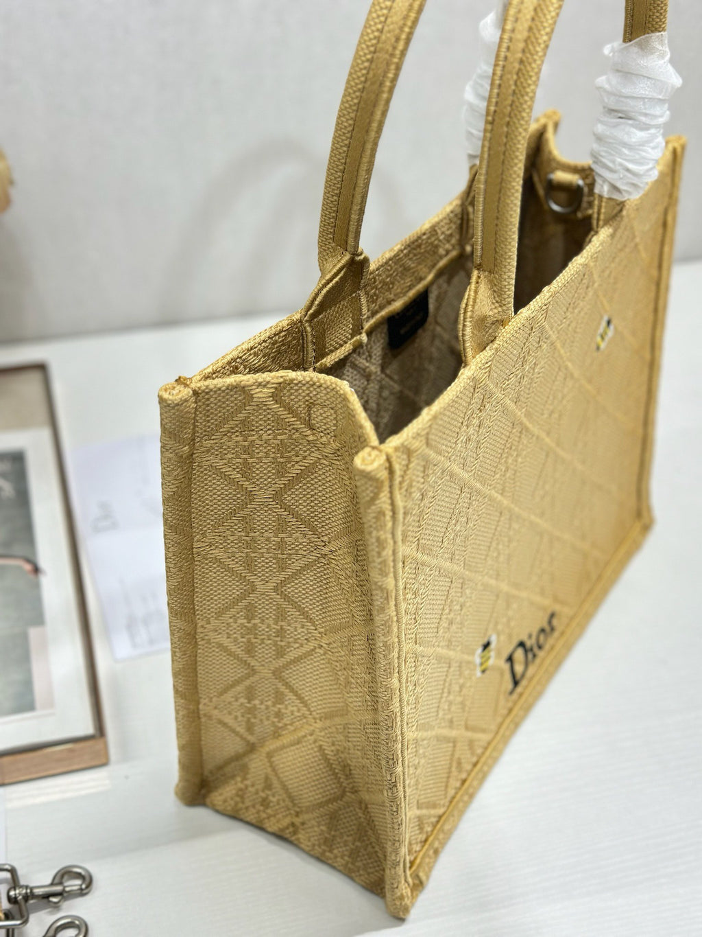 Dior gold handbag side view with open top, interior panel, and front Dior logo.