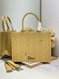 Dior textured gold handbag with top handles, front Dior logo patch, and small charm.