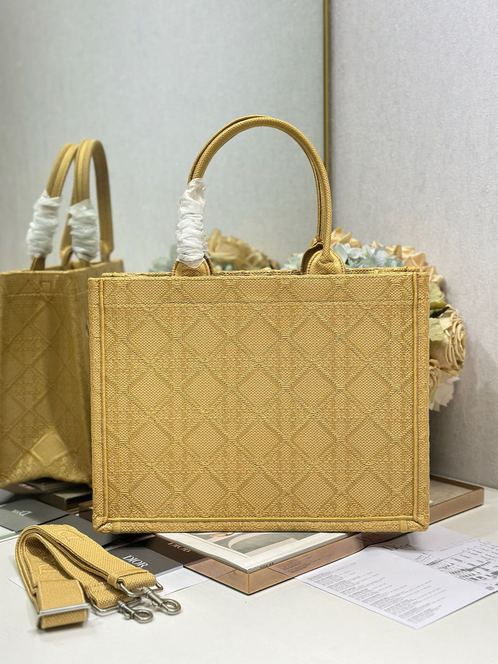 Dior gold handbag with top handles, quilted texture, and Dior charm on front.