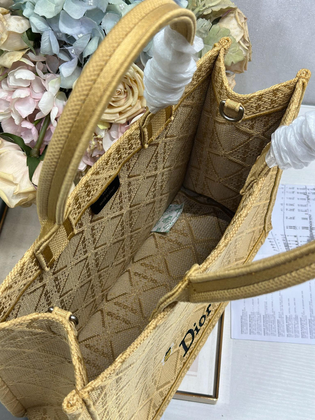 Dior gold handbag detail with top handle, white tassel tie, and textured side panels.
