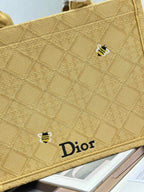 Dior gold handbag close-up of textured fabric, small charm, and Dior logo label.