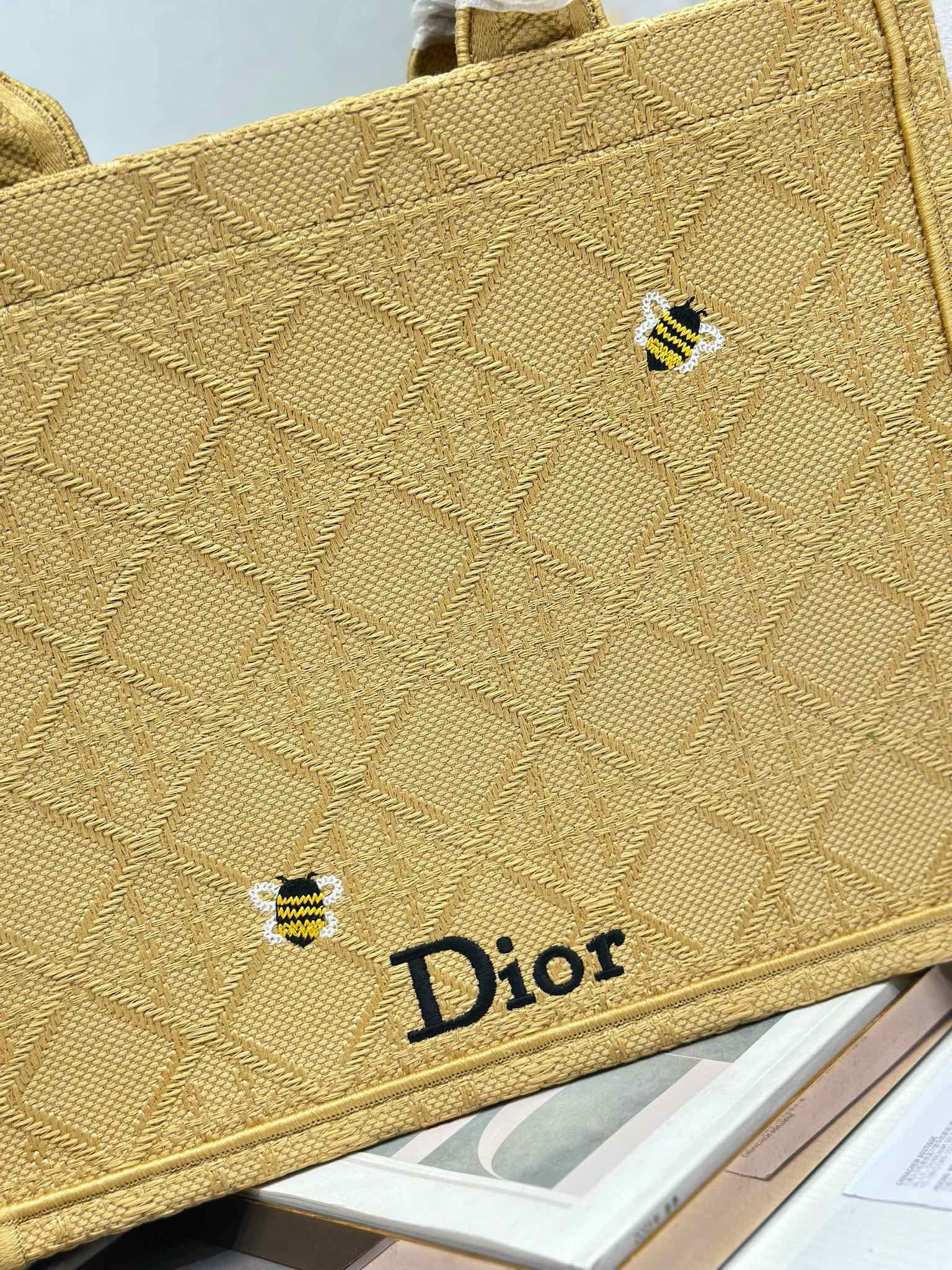 Dior gold handbag close-up of textured fabric, small charm, and Dior logo label.
