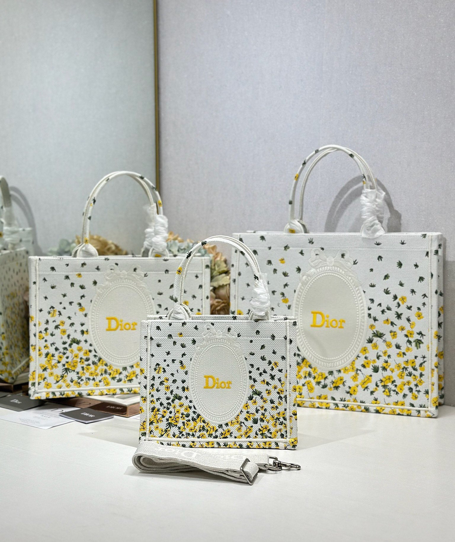 White Dior tote bags with yellow speckled print and oval logo medallions