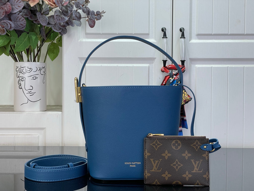 Blue leather bucket bag with gold-tone handles and attached small monogram pouch