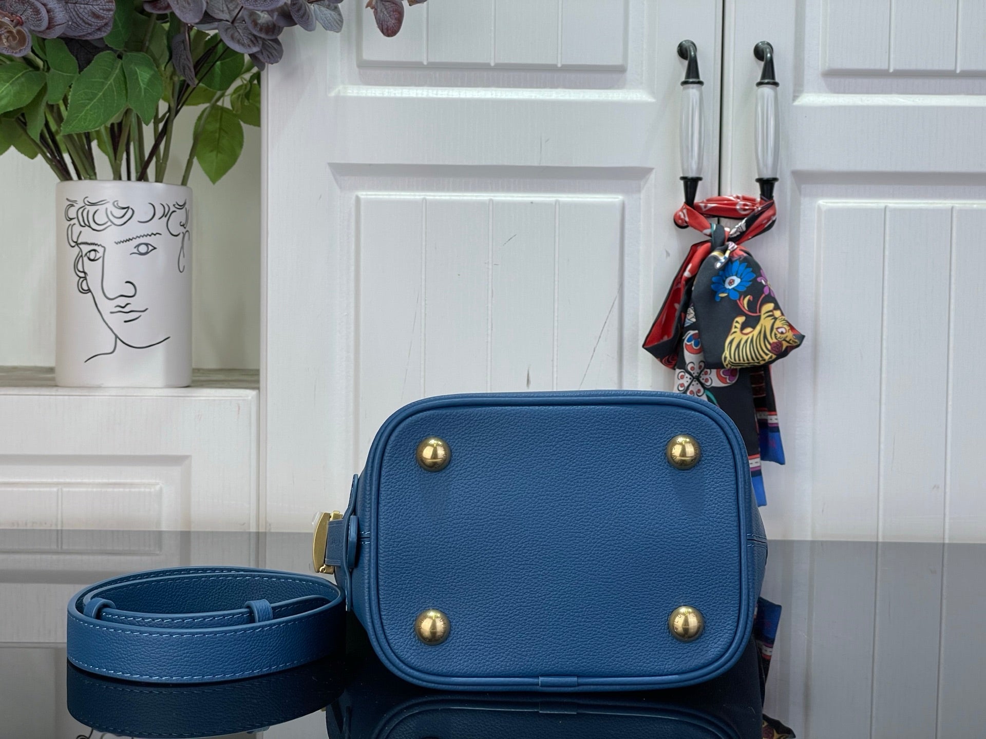 Blue flap crossbody bag with gold-tone studs and attached strap pouch