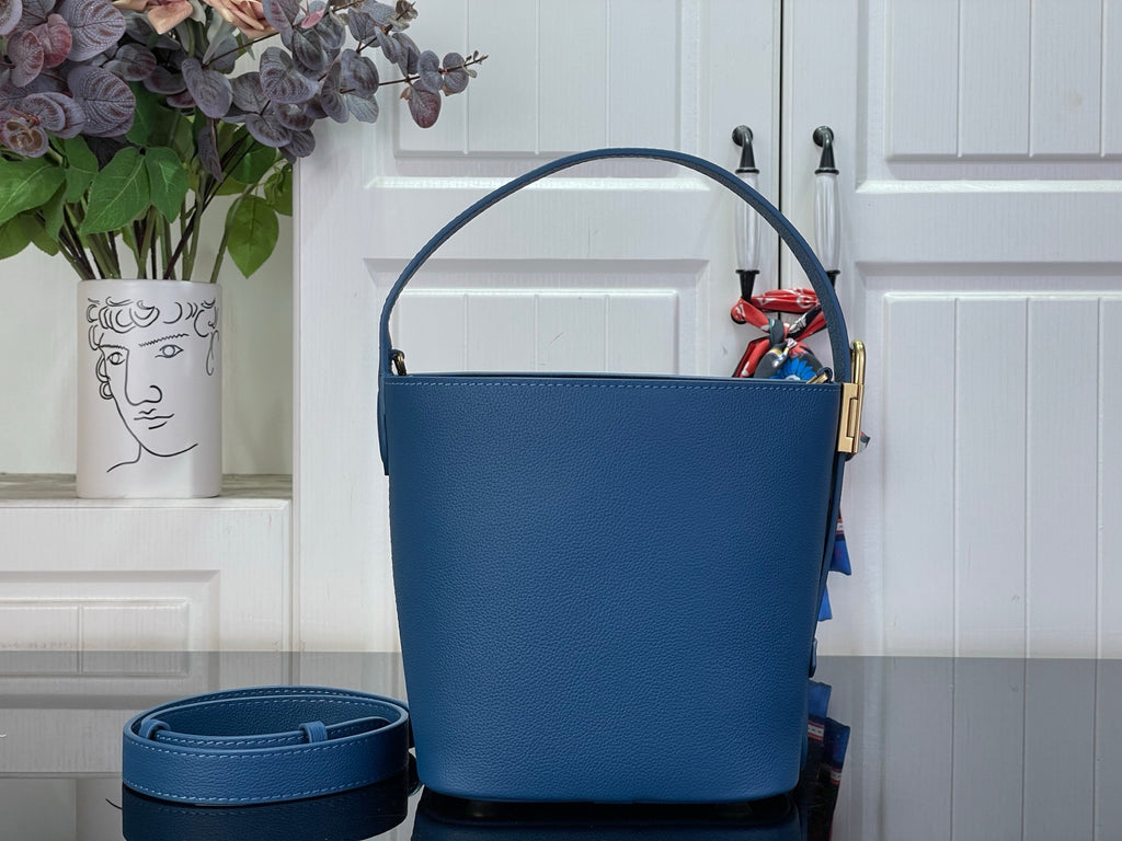 Blue bucket bag with gold-tone handle hardware and hanging strap detail