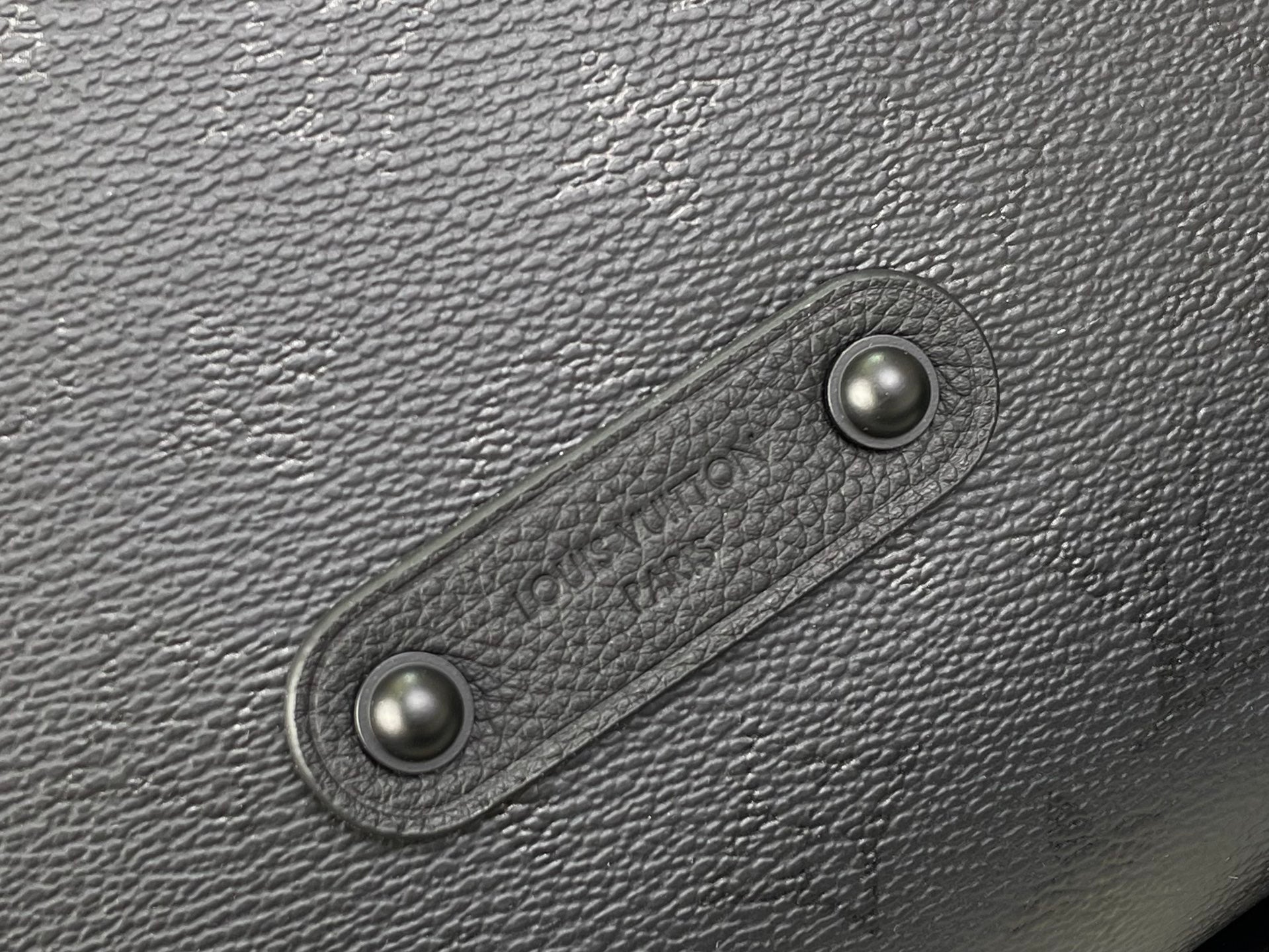 Louis Vuitton hobo bag close-up of snap hardware on dark textured leather