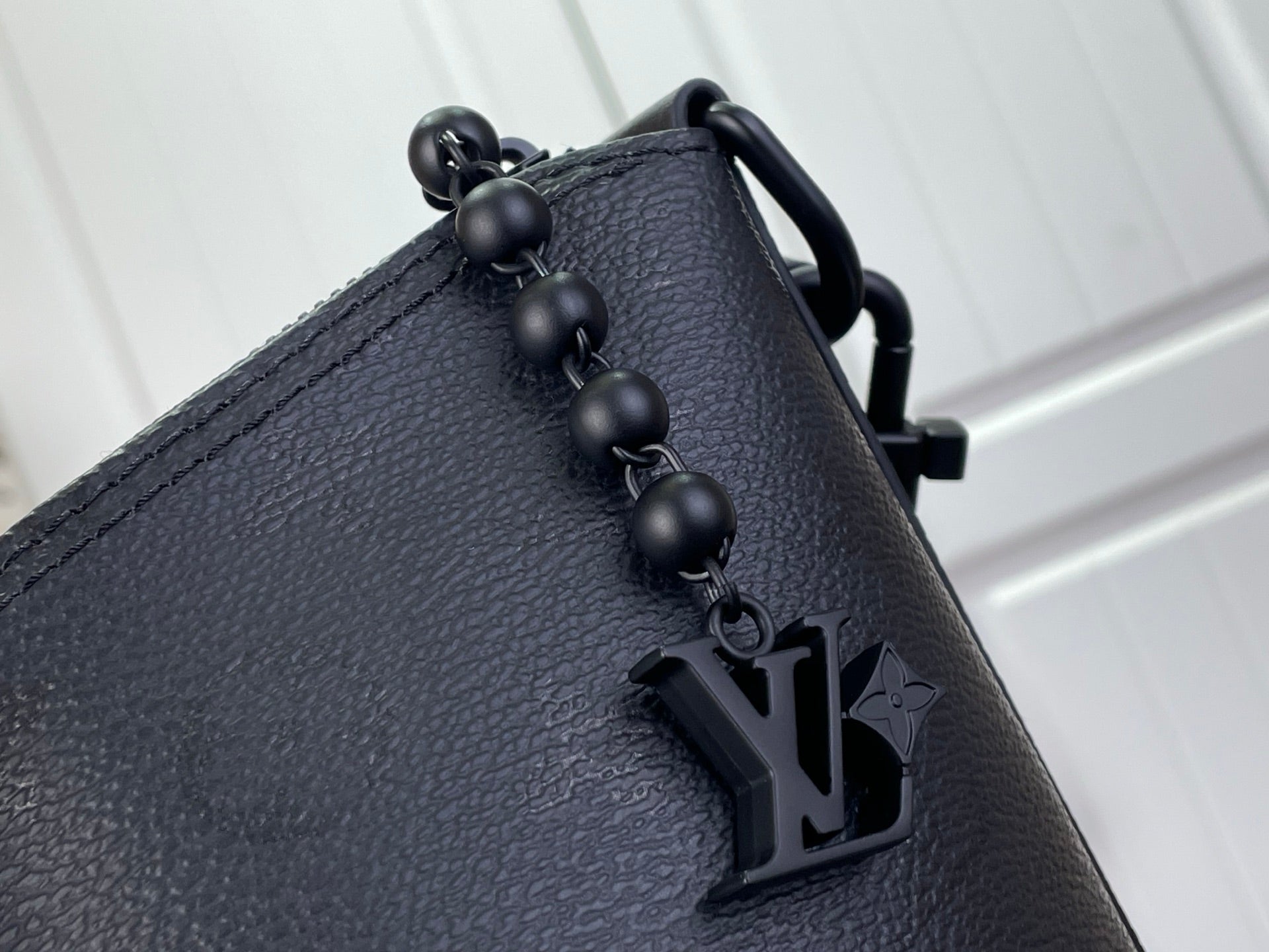Louis Vuitton hobo bag close-up of top handle hardware with LV charm