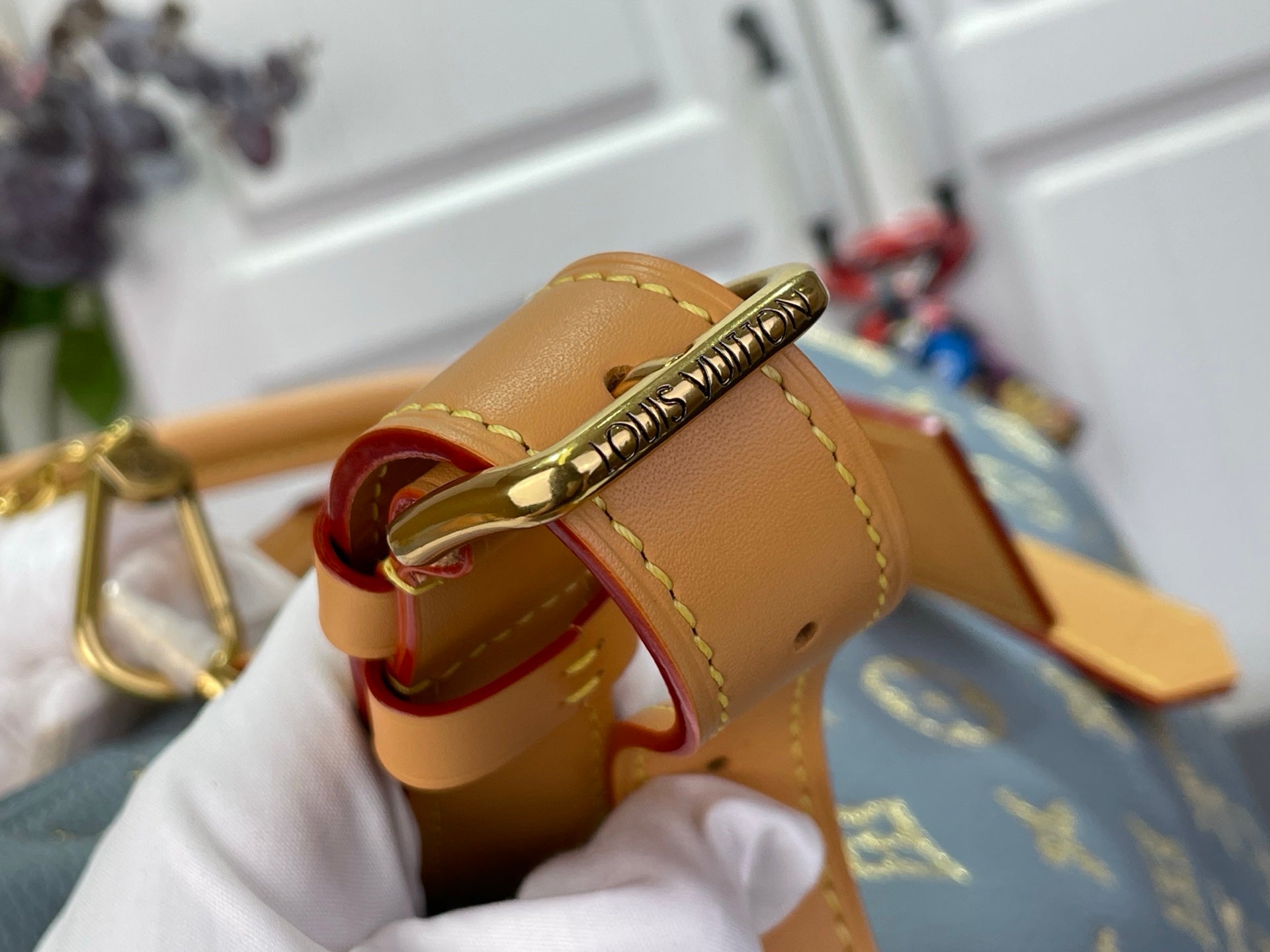 Louis Vuitton bag strap detail with gold buckle hardware and tan leather trim