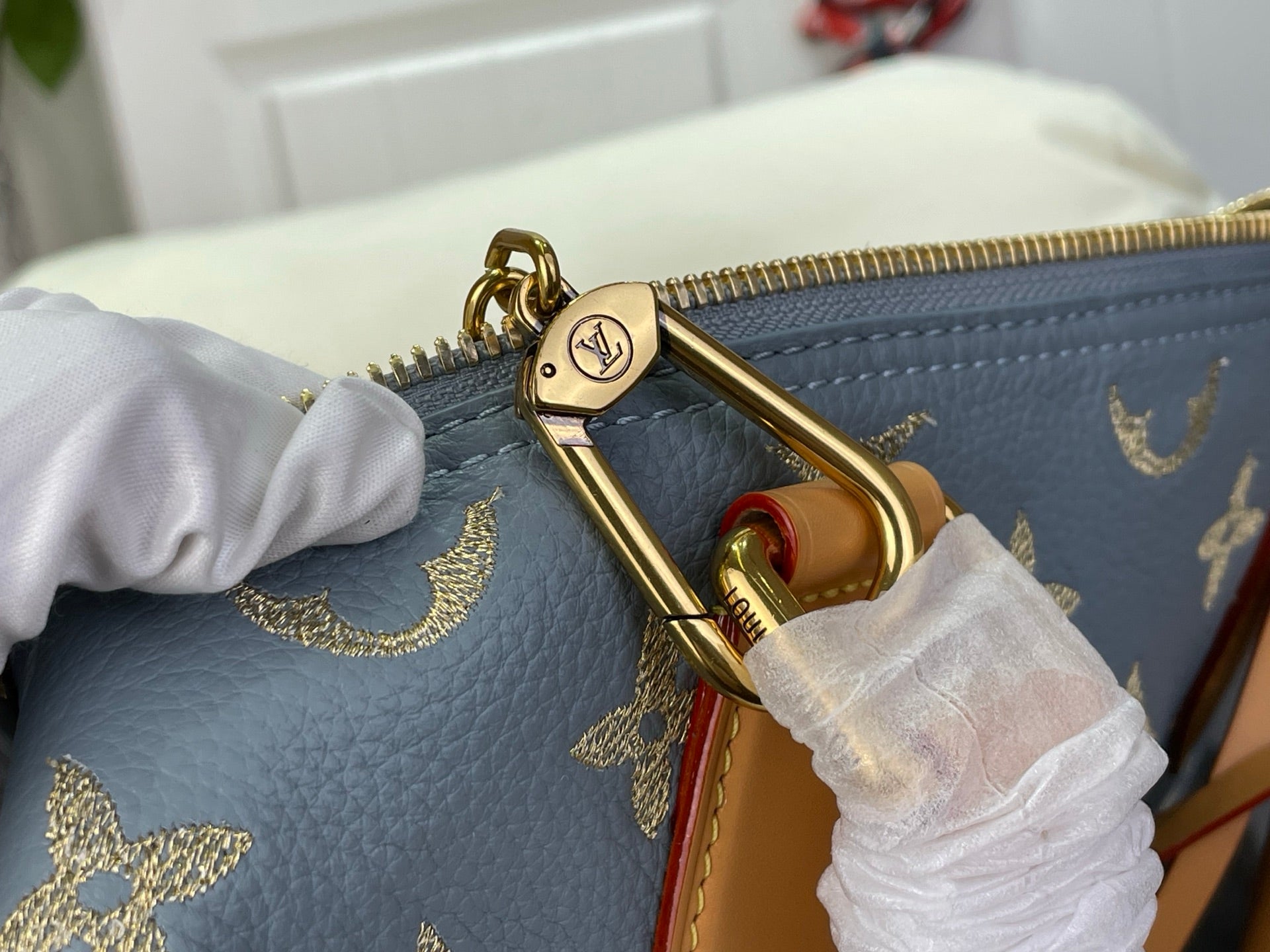 Louis Vuitton bag zipper pull and gold D-ring hardware with blue monogram and tan strap