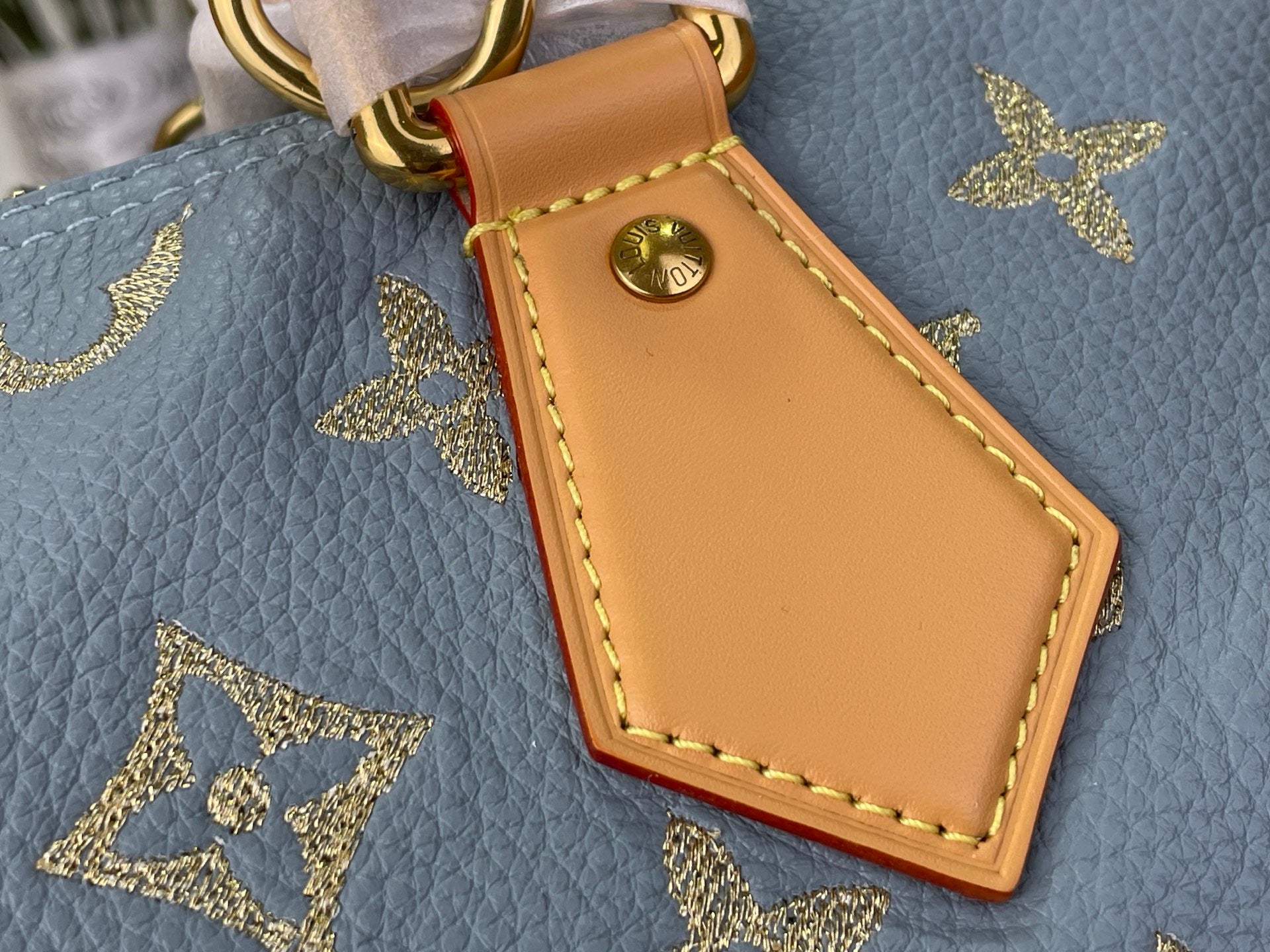 Louis Vuitton tan leather luggage-tag charm with gold button detail on light blue monogram