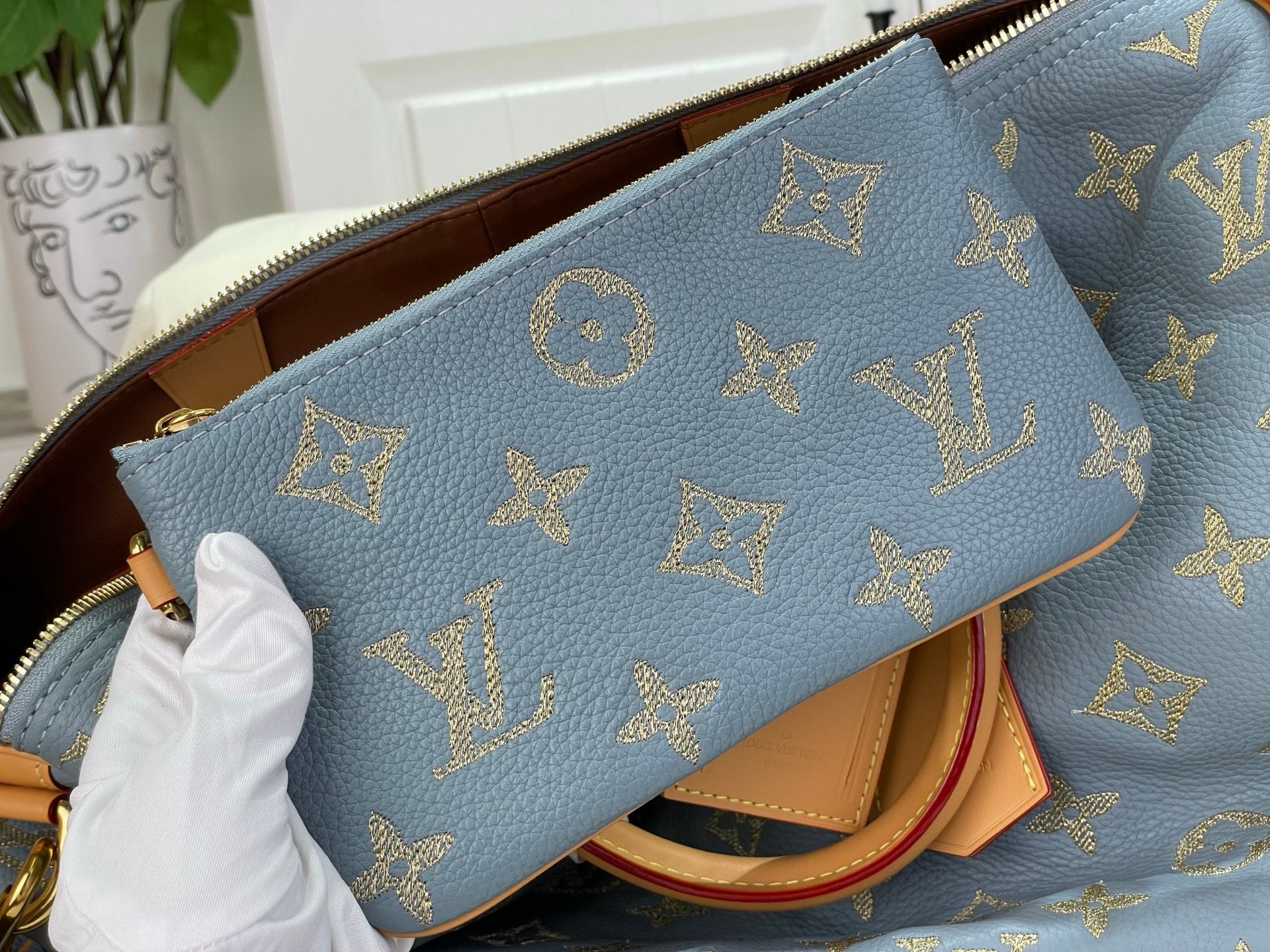Louis Vuitton bag front with light blue leather and gold monogram icons pattern